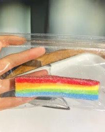 Colorful striped candy in a clear plastic bag held by a hand.