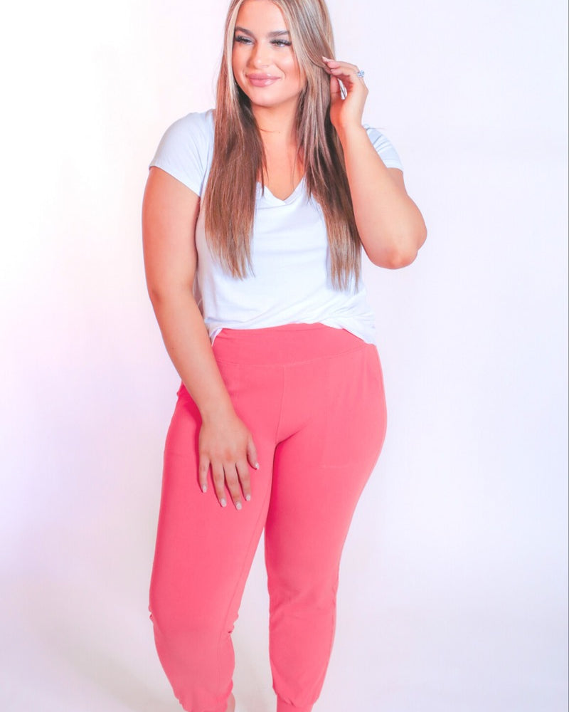 coral high-rise joggers crafted on smooth stretch fabric with a 3" waistband, side pockets, interior waistband back pocket, contoured back seam detail, tapered leg, and cuffed ankles