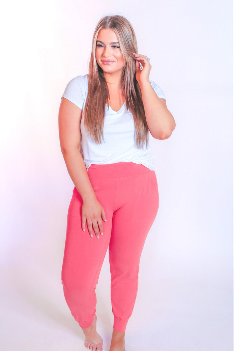 coral high-rise joggers crafted on smooth stretch fabric with a 3" waistband, side pockets, interior waistband back pocket, contoured back seam detail, tapered leg, and cuffed ankles