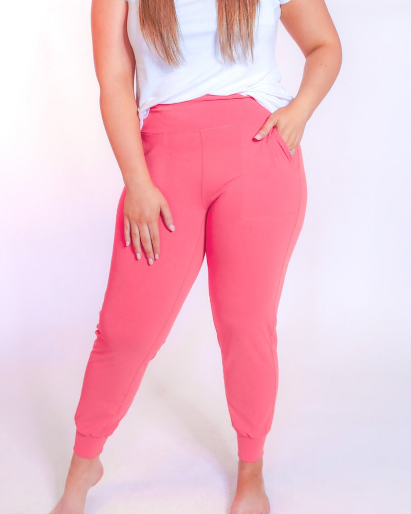 coral high-rise joggers crafted on smooth stretch fabric with a 3" waistband, side pockets, interior waistband back pocket, contoured back seam detail, tapered leg, and cuffed ankles