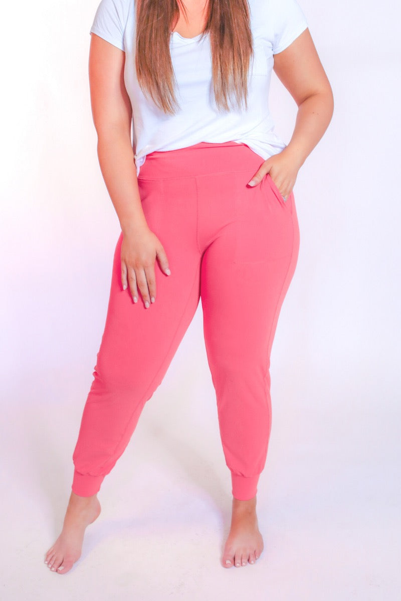coral high-rise joggers crafted on smooth stretch fabric with a 3" waistband, side pockets, interior waistband back pocket, contoured back seam detail, tapered leg, and cuffed ankles