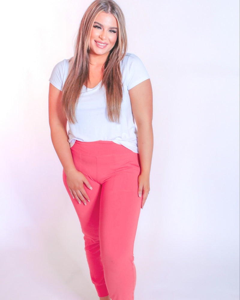 coral high-rise joggers crafted on smooth stretch fabric with a 3" waistband, side pockets, interior waistband back pocket, contoured back seam detail, tapered leg, and cuffed ankles