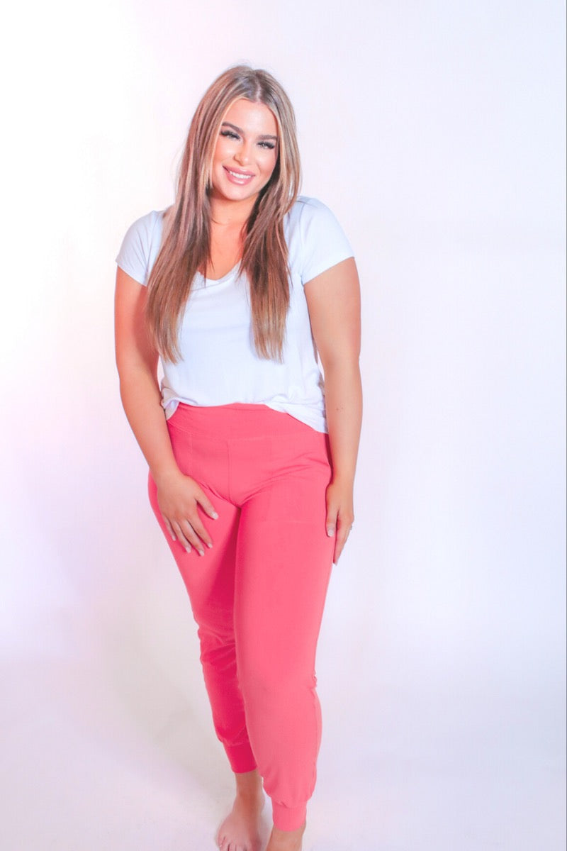 coral high-rise joggers crafted on smooth stretch fabric with a 3" waistband, side pockets, interior waistband back pocket, contoured back seam detail, tapered leg, and cuffed ankles