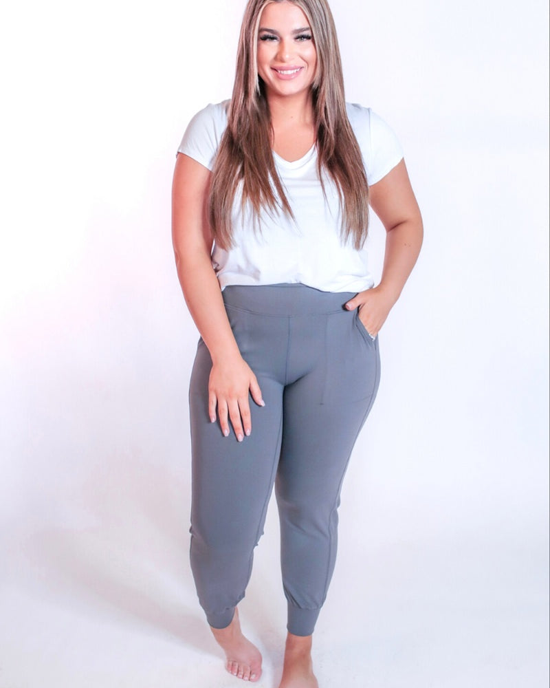 grey high-rise joggers crafted on smooth stretch fabric with a 3" waistband, side pockets, interior waistband back pocket, contoured back seam detail, tapered leg, and cuffed ankles
