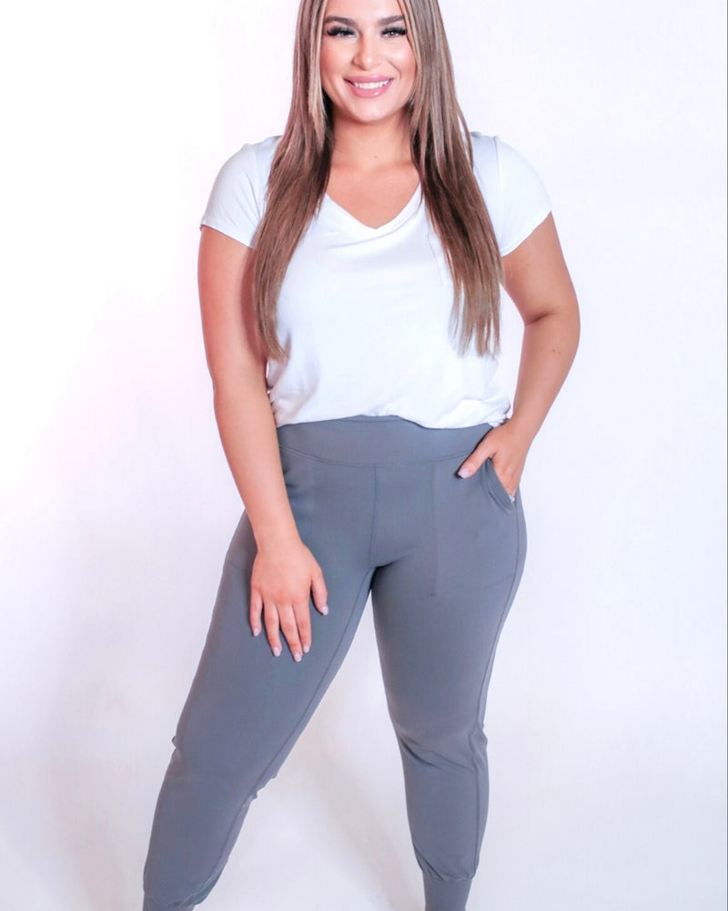 grey high-rise joggers crafted on smooth stretch fabric with a 3" waistband, side pockets, interior waistband back pocket, contoured back seam detail, tapered leg, and cuffed ankles