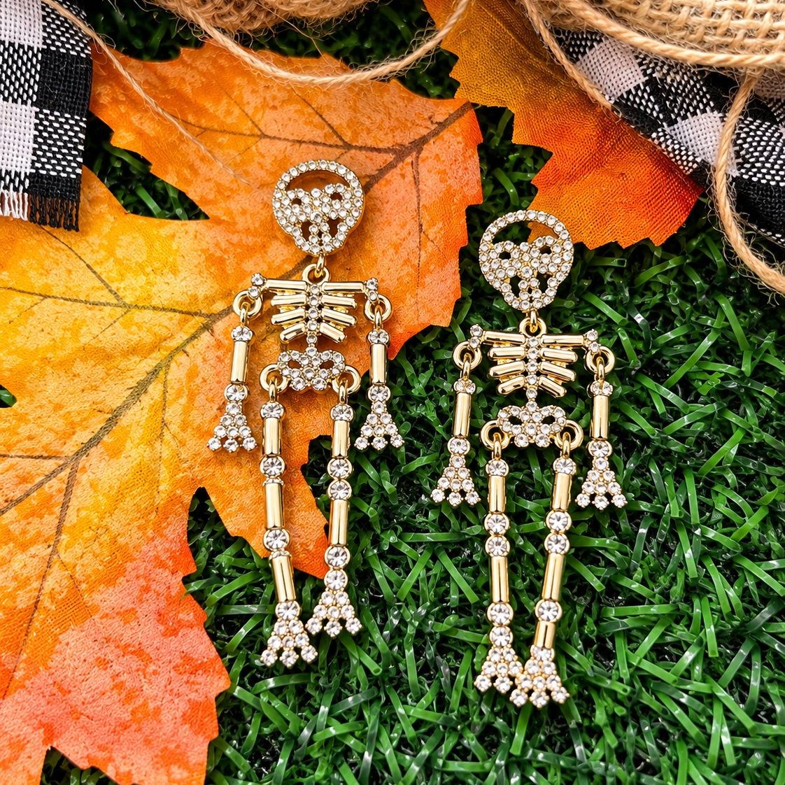 gold-plated post-back skeleton-shaped dangle earrings with rhinestone accents, skull stud tops, articulated bone design, matching barrel backs, and nickel/lead compliant construction in gold