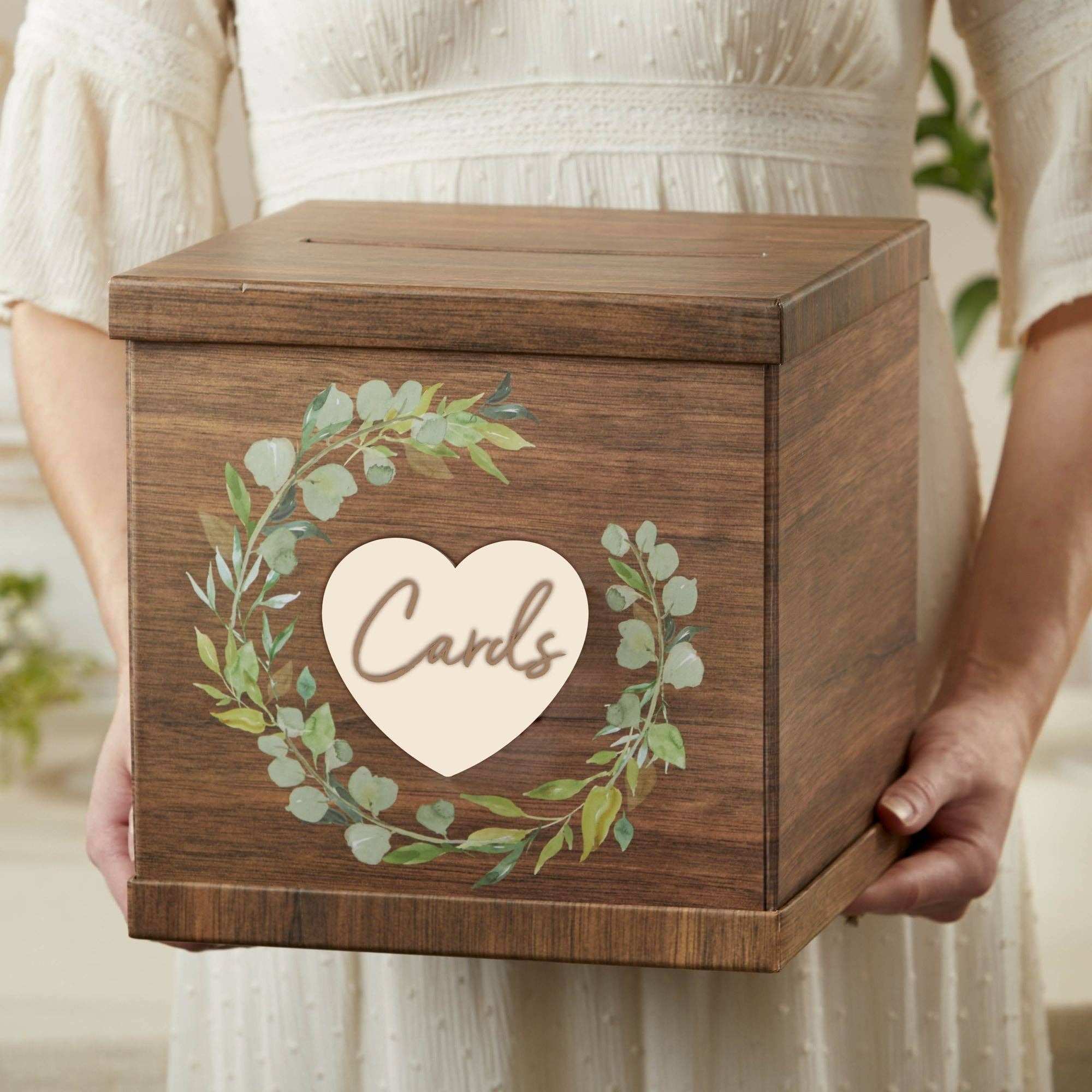 Wooden box with decorative heart and foliage design held by a person