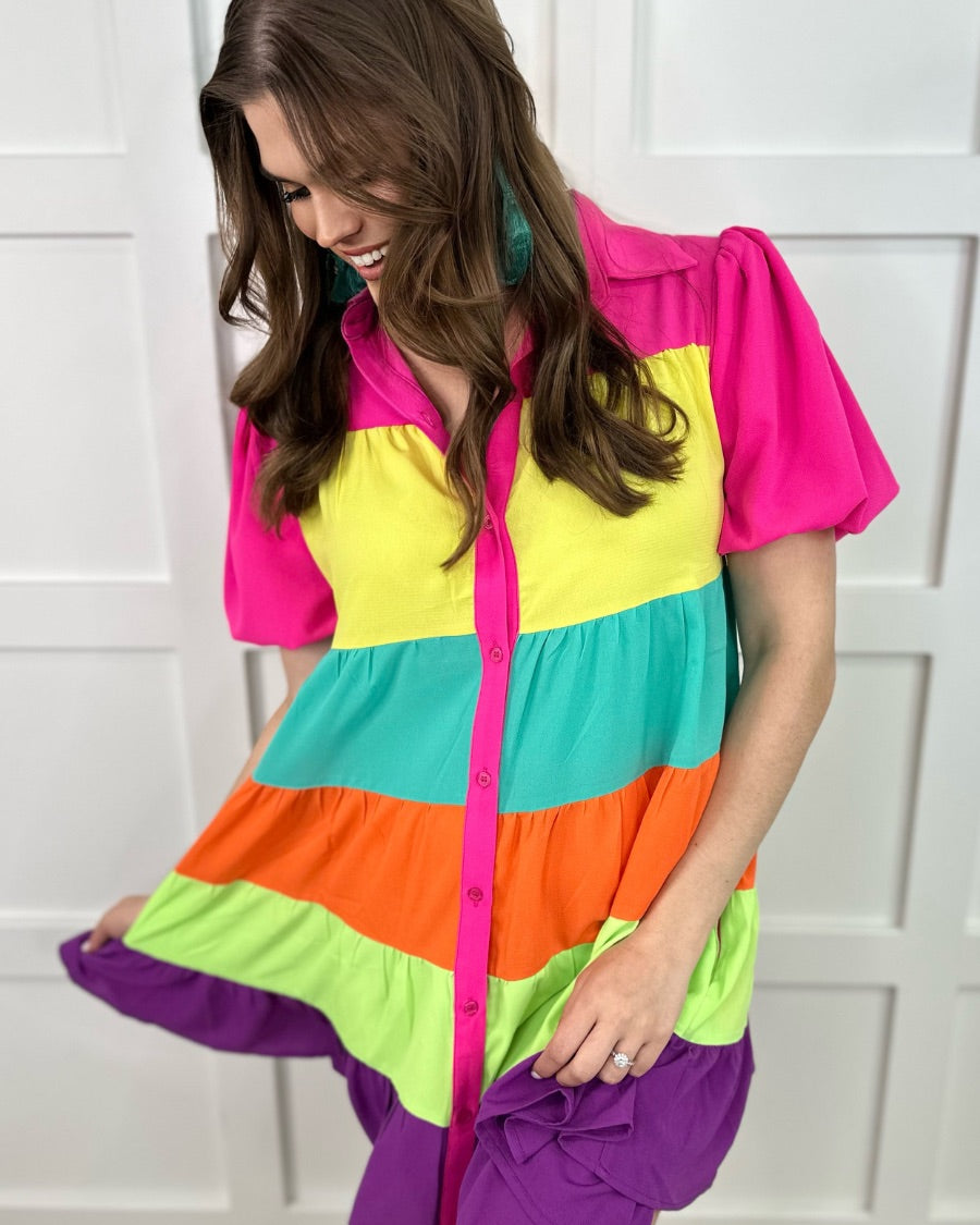 a tiered multicolored dress with convenient pockets, playful puff sleeves, a trendy collar, and a functional button-down design front in vibrant pink, yellow, mint, orange, green, and purple stripes with pink accent trim