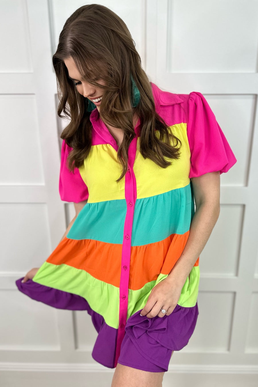 a tiered multicolored dress with convenient pockets, playful puff sleeves, a trendy collar, and a functional button-down design front in vibrant pink, yellow, mint, orange, green, and purple stripes with pink accent trim