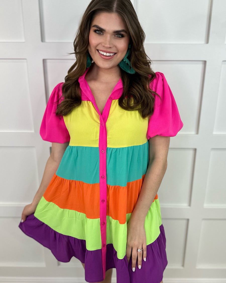 a tiered multicolored dress with convenient pockets, playful puff sleeves, a trendy collar, and a functional button-down design front in vibrant pink, yellow, mint, orange, green, and purple stripes with pink accent trim