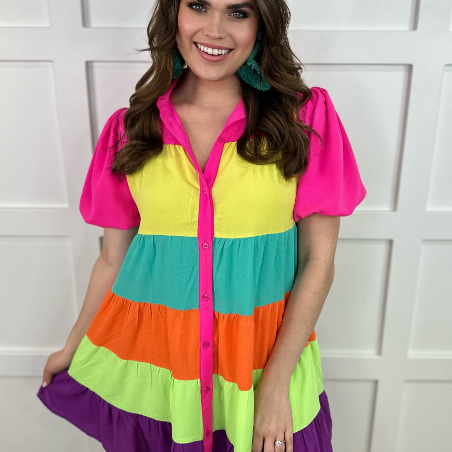 a tiered multicolored dress with convenient pockets, playful puff sleeves, a trendy collar, and a functional button-down design front in vibrant pink, yellow, mint, orange, green, and purple stripes with pink accent trim