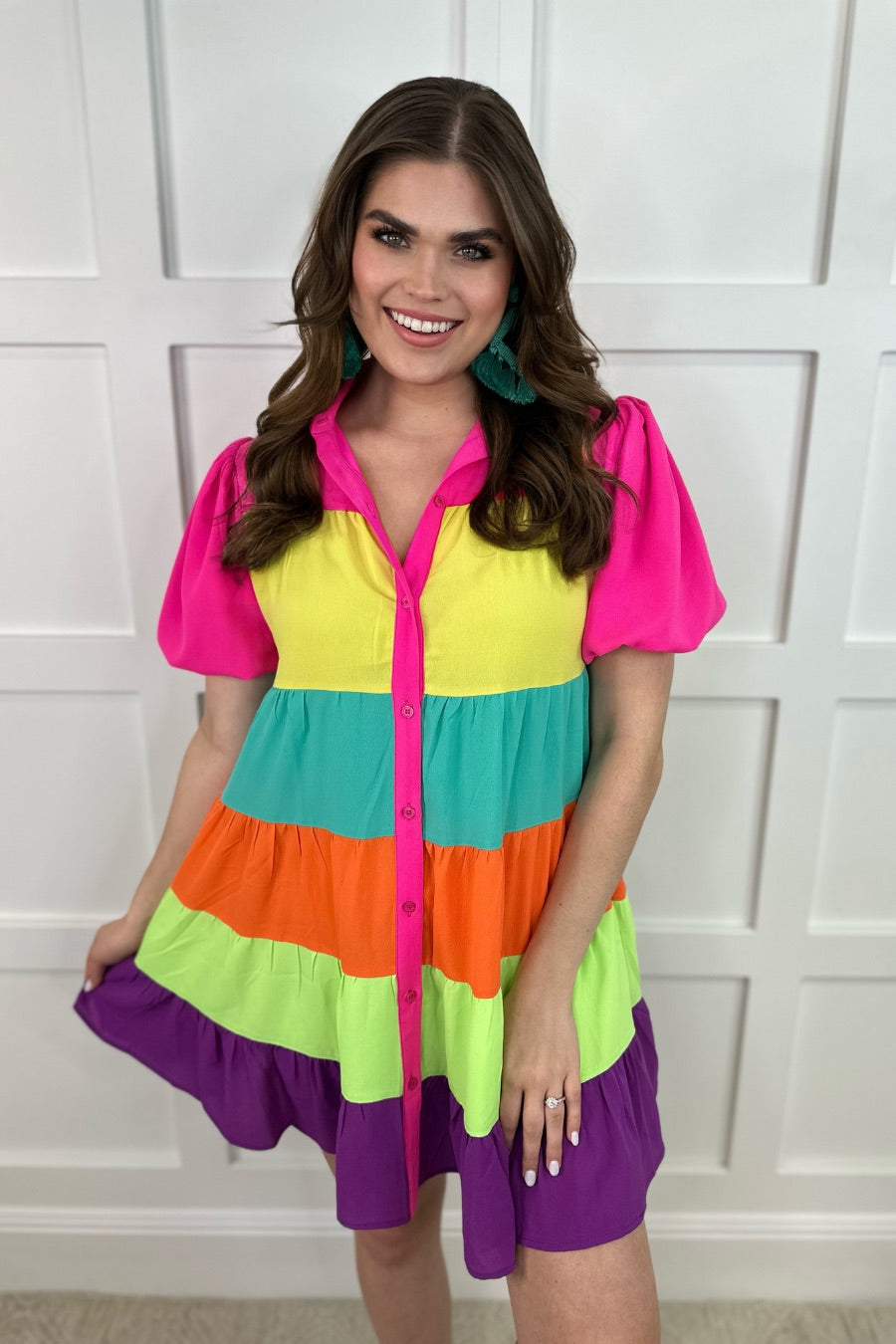 a tiered multicolored dress with convenient pockets, playful puff sleeves, a trendy collar, and a functional button-down design front in vibrant pink, yellow, mint, orange, green, and purple stripes with pink accent trim