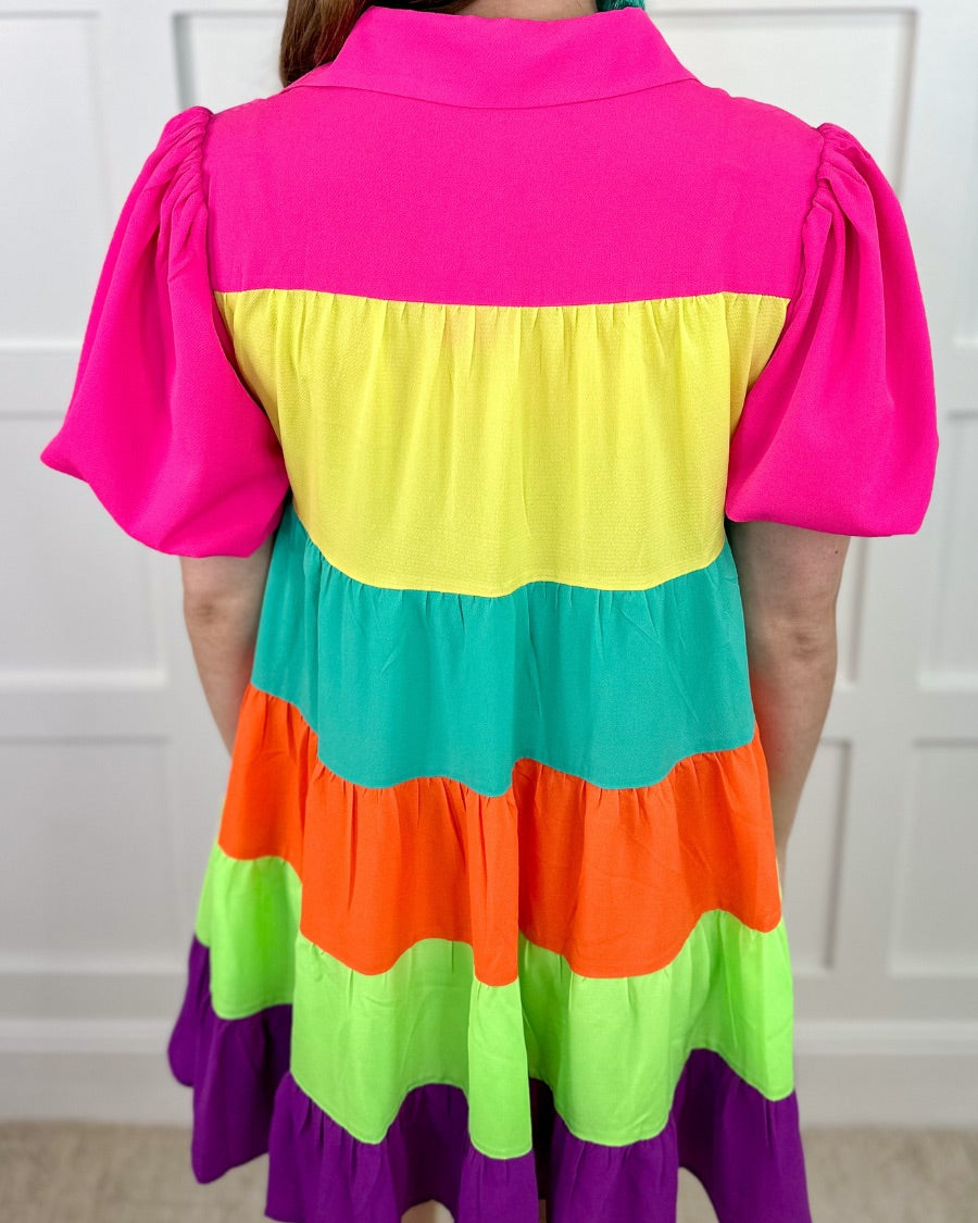 a tiered multicolored dress with convenient pockets, playful puff sleeves, a trendy collar, and a functional button-down design front in vibrant pink, yellow, mint, orange, green, and purple stripes with pink accent trim