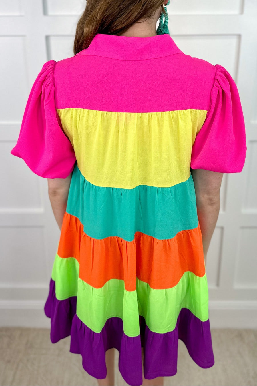a tiered multicolored dress with convenient pockets, playful puff sleeves, a trendy collar, and a functional button-down design front in vibrant pink, yellow, mint, orange, green, and purple stripes with pink accent trim