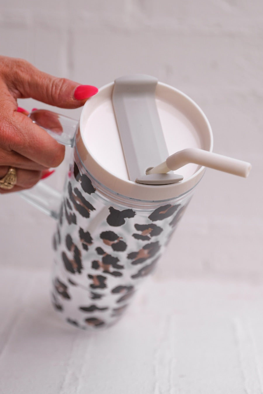 40-ounce black and brown animal print acrylic tumbler with a reusable straw (ivory), flexible mouthpiece (ivory), handle, screw-on lid (ivory with a grey rotate lid tab), and car cup holder compatible