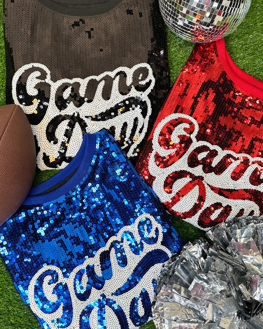 a full sequin design top on a solid color with the words 'Game Day" on the center front outlined in white sequins, a boxy fit, and a lined interior in black, red, and royal blue