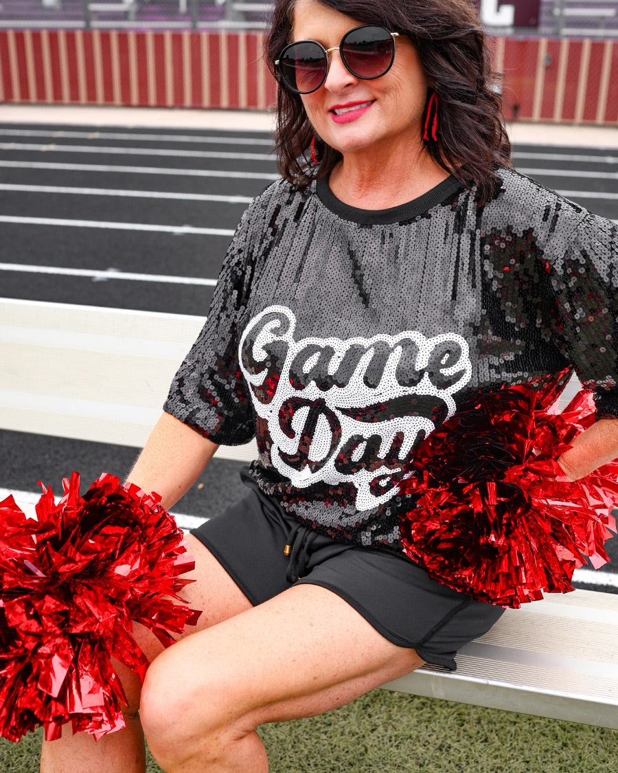 a full sequin design top on a solid color with the words 'Game Day" on the center front outlined in white sequins, a boxy fit, and a lined interior in black