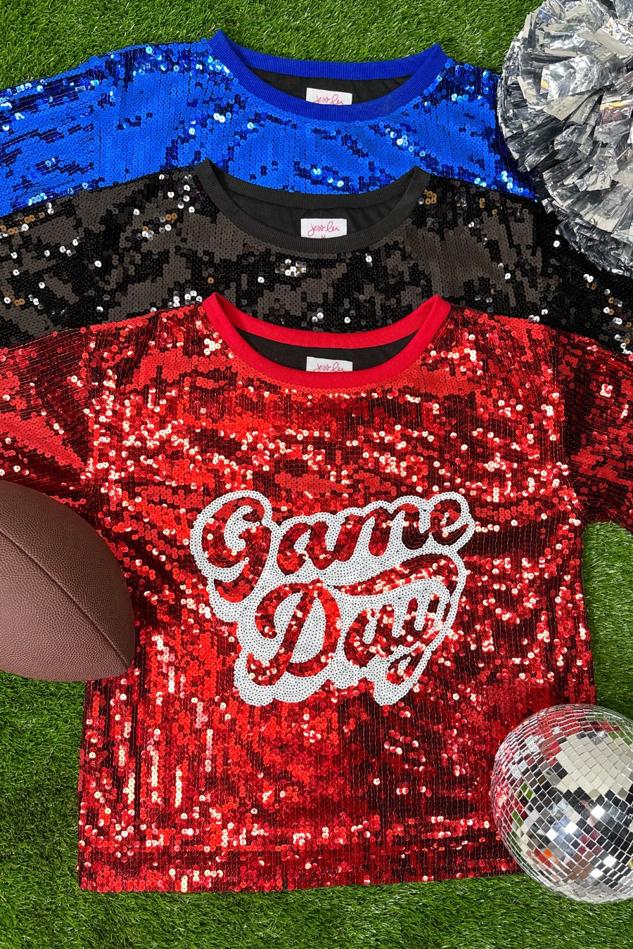 a full sequin design top on a solid color with the words 'Game Day" on the center front outlined in white sequins, a boxy fit, and a lined interior in black, red, and royal blue