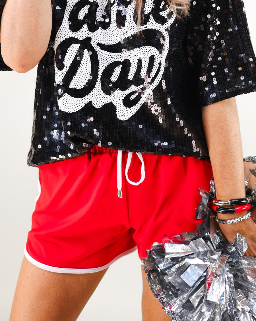 a full sequin design top on a solid color with the words 'Game Day" on the center front outlined in white sequins, a boxy fit, and a lined interior in black