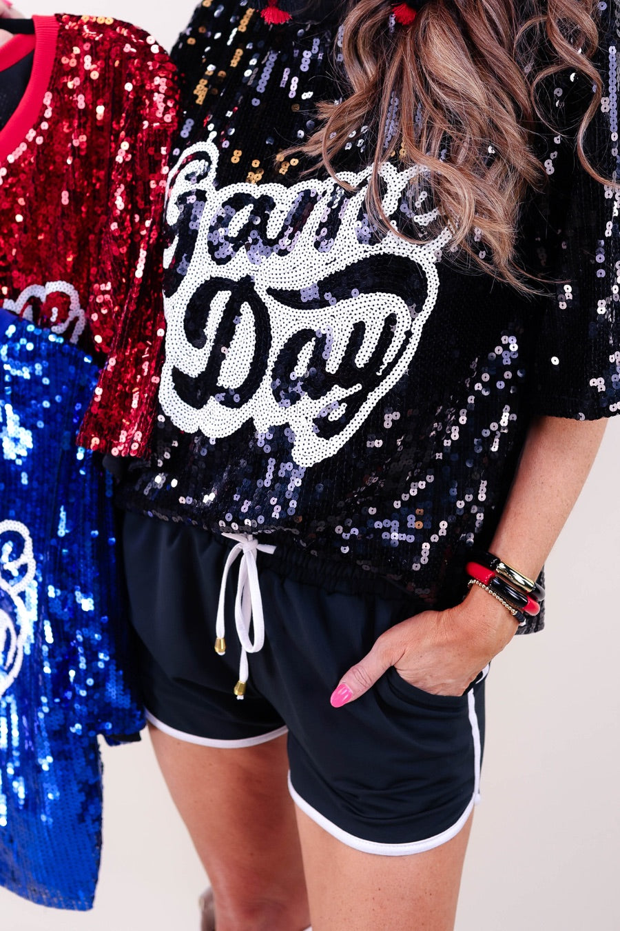 a full sequin design top on a solid color with the words 'Game Day" on the center front outlined in white sequins, a boxy fit, and a lined interior in black, red, and royal blue
