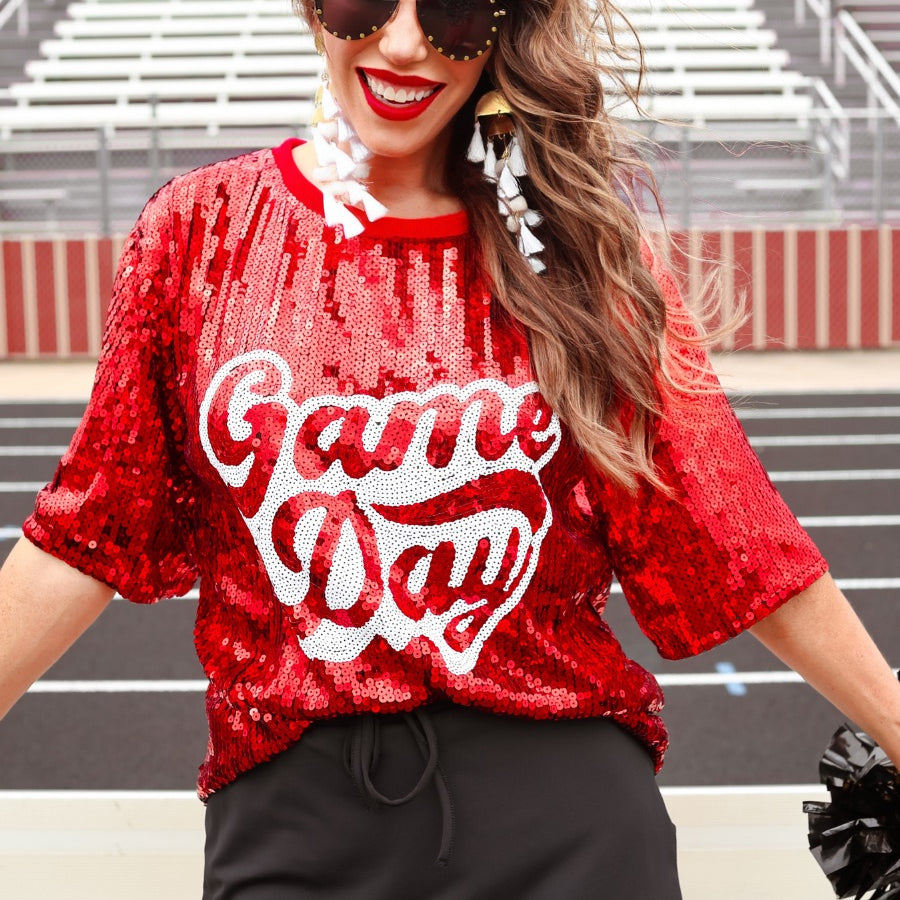 a full sequin design top on a solid color with the words 'Game Day" on the center front outlined in white sequins, a boxy fit, and a lined interior in red