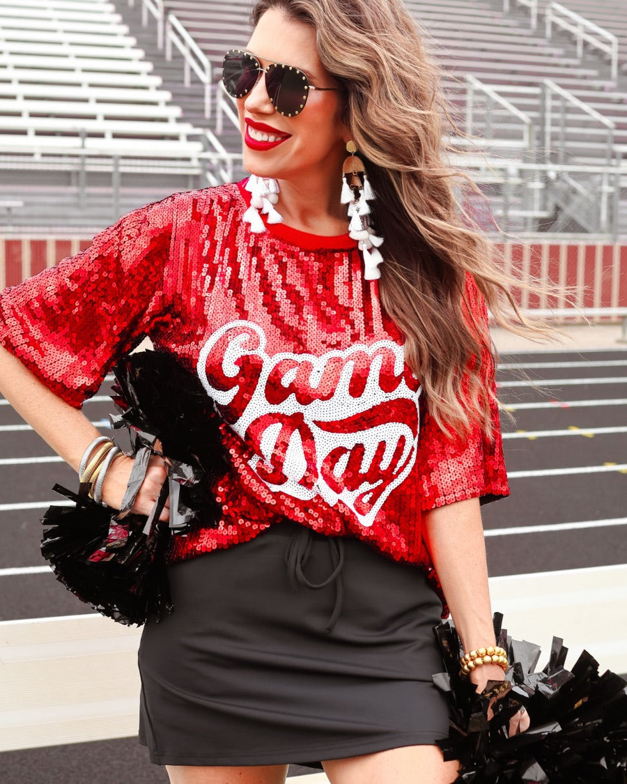 a full sequin design top on a solid color with the words 'Game Day" on the center front outlined in white sequins, a boxy fit, and a lined interior in red