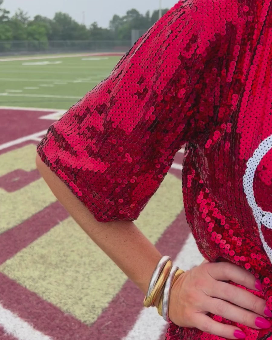 a full sequin design top on a solid color with the words 'Game Day" on the center front outlined in white sequins, a boxy fit, and a lined interior in red