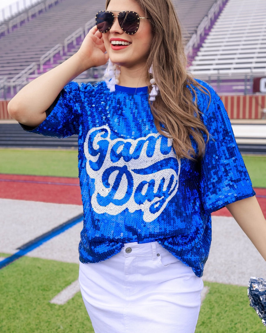 a full sequin design top on a solid color with the words 'Game Day" on the center front outlined in white sequins, a boxy fit, and a lined interior in royal blue
