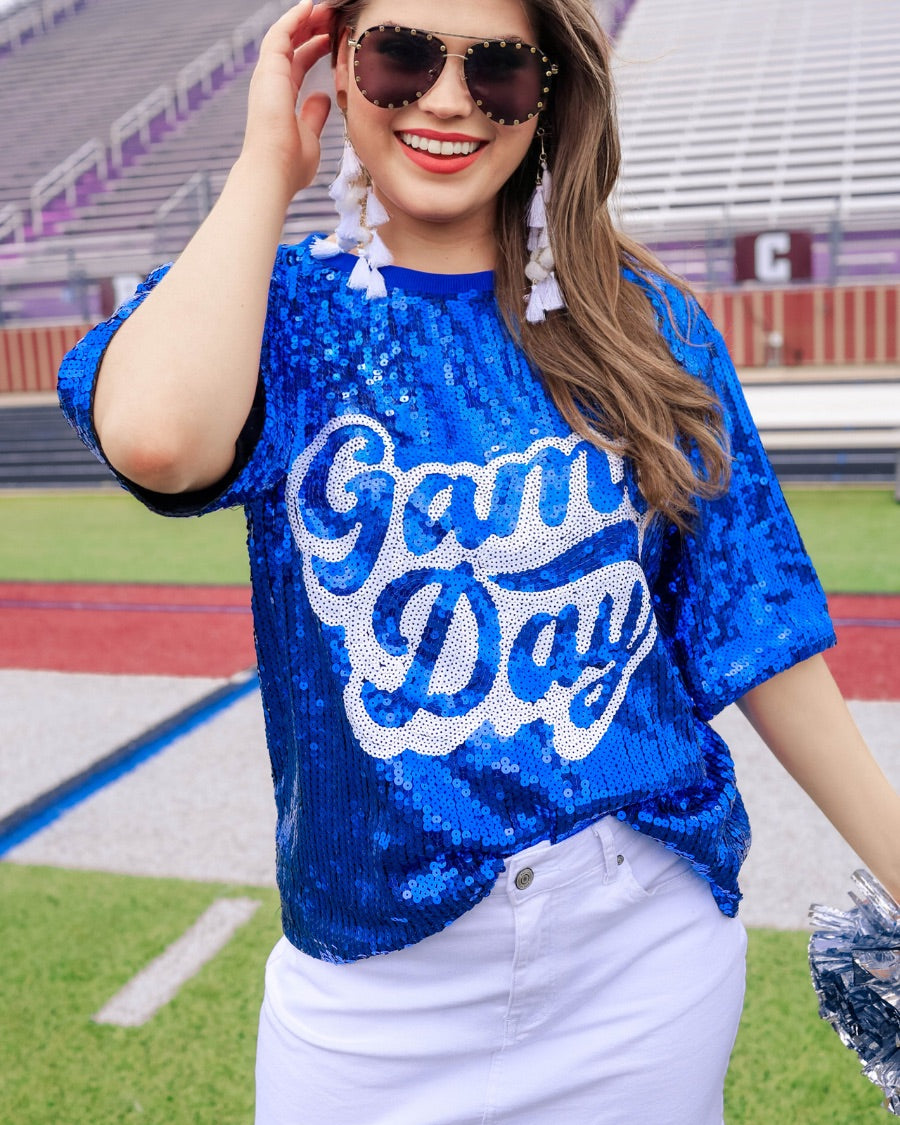 a full sequin design top on a solid color with the words 'Game Day" on the center front outlined in white sequins, a boxy fit, and a lined interior in royal blue