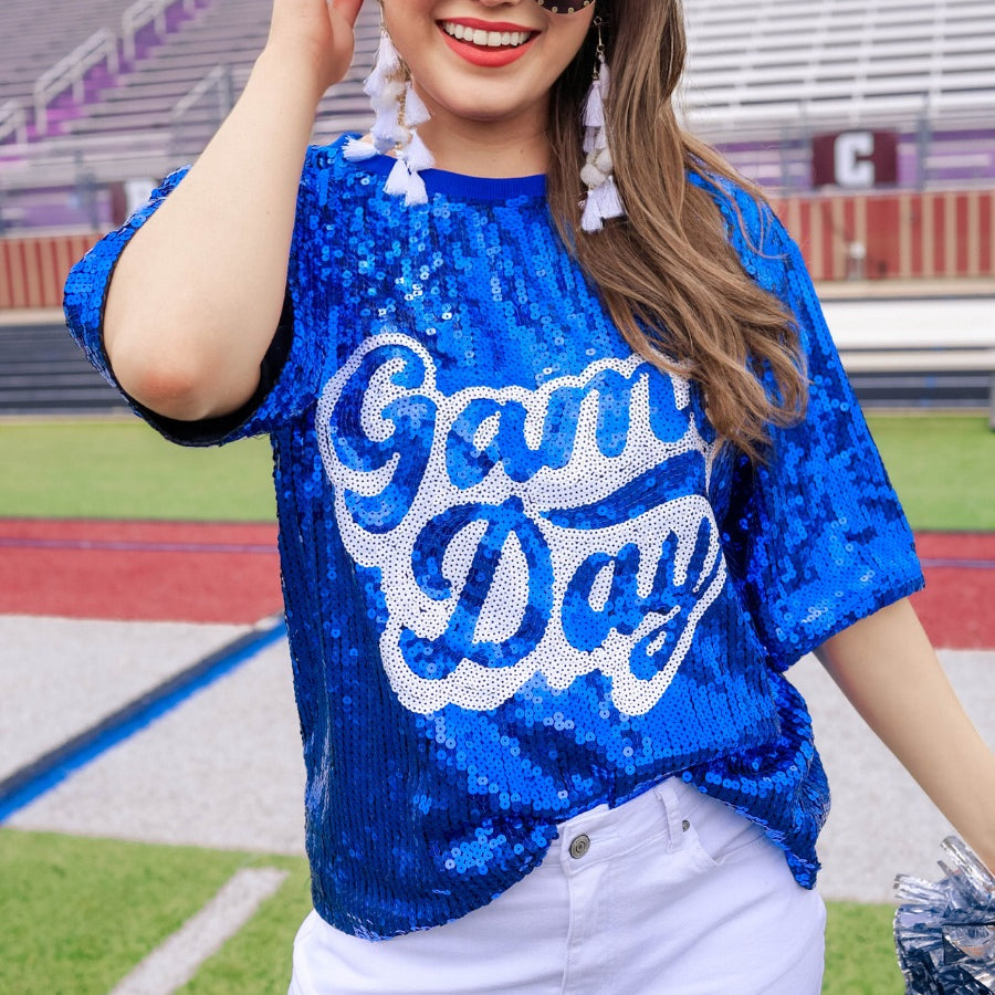 a full sequin design top on a solid color with the words 'Game Day" on the center front outlined in white sequins, a boxy fit, and a lined interior in royal blue