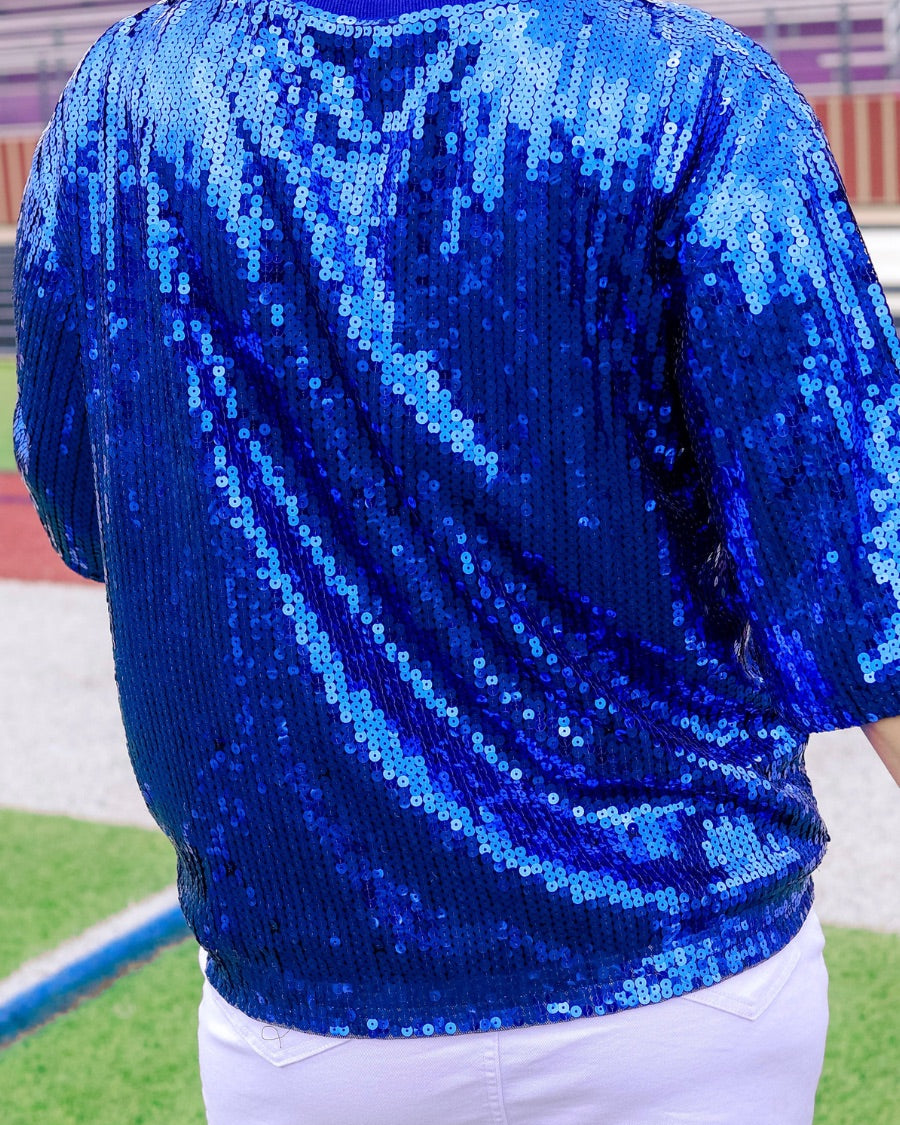 a full sequin design top on a solid color with the words 'Game Day" on the center front outlined in white sequins, a boxy fit, and a lined interior in royal blue