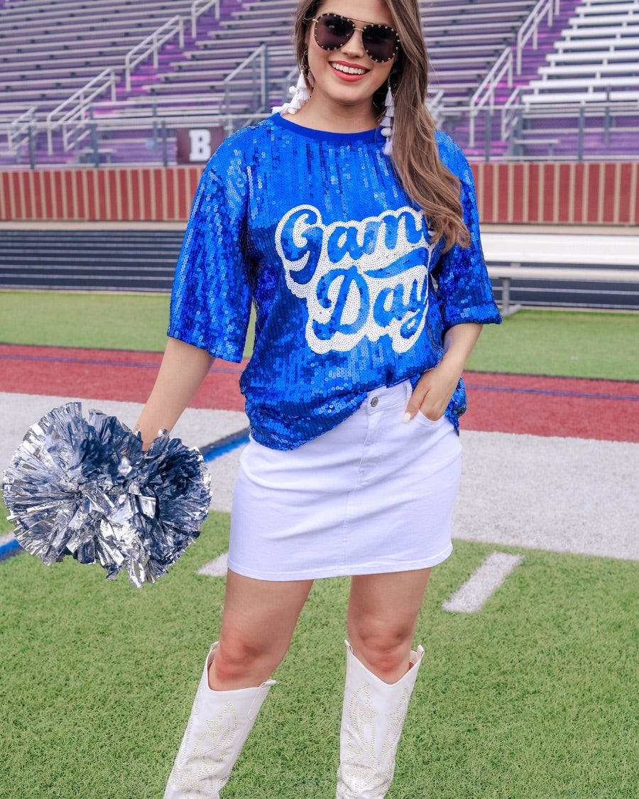 a full sequin design top on a solid color with the words 'Game Day" on the center front outlined in white sequins, a boxy fit, and a lined interior in royal blue