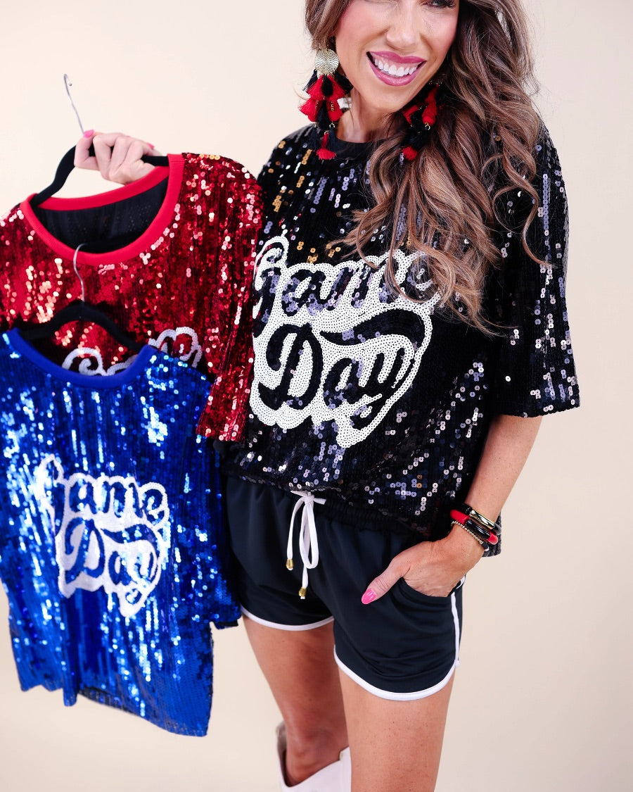 a full sequin design top on a solid color with the words 'Game Day" on the center front outlined in white sequins, a boxy fit, and a lined interior in black, red, and royal blue