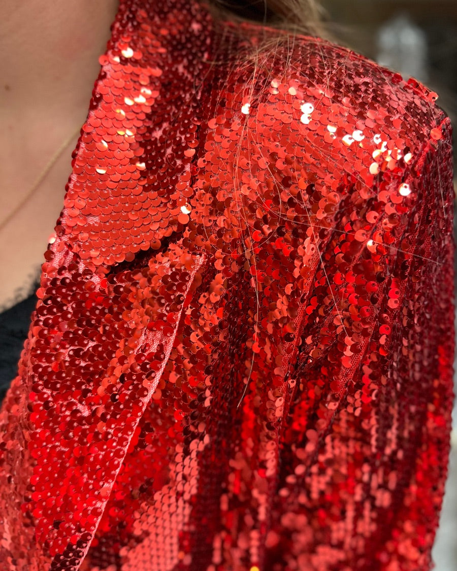 a full sequin-covered long-sleeve blazer with a structured collar, subtle shoulder pads, a smooth interior lining, and a center back vent in red