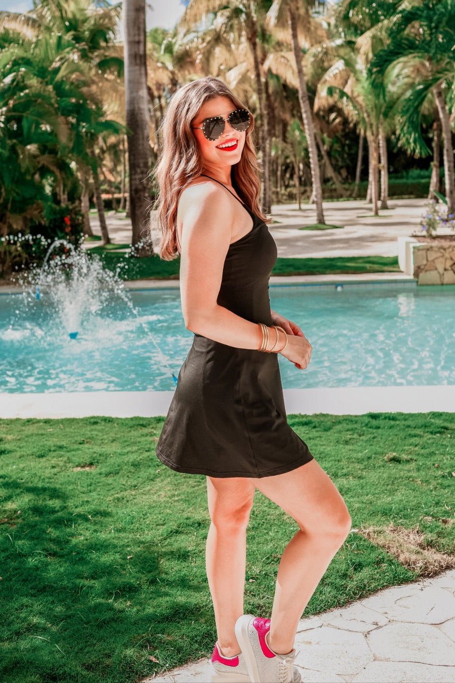 a black sleeveless tennis dress designed with built-in shorts featuring hidden side pockets, adjustable crisscross straps, and built-in shelf bra