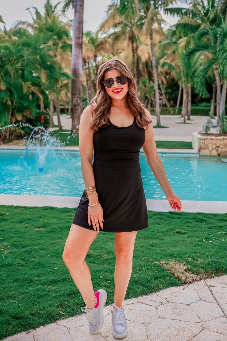 a black sleeveless tennis dress designed with built-in shorts featuring hidden side pockets, adjustable crisscross straps, and built-in shelf bra
