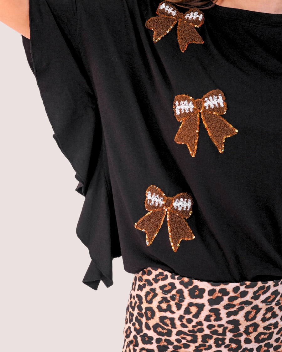 fluttery ruffle short-sleeve top with a mom crop length, sewn-on chenille football bow patches outlined in sequins on a soft, stretch-knit fabric in black