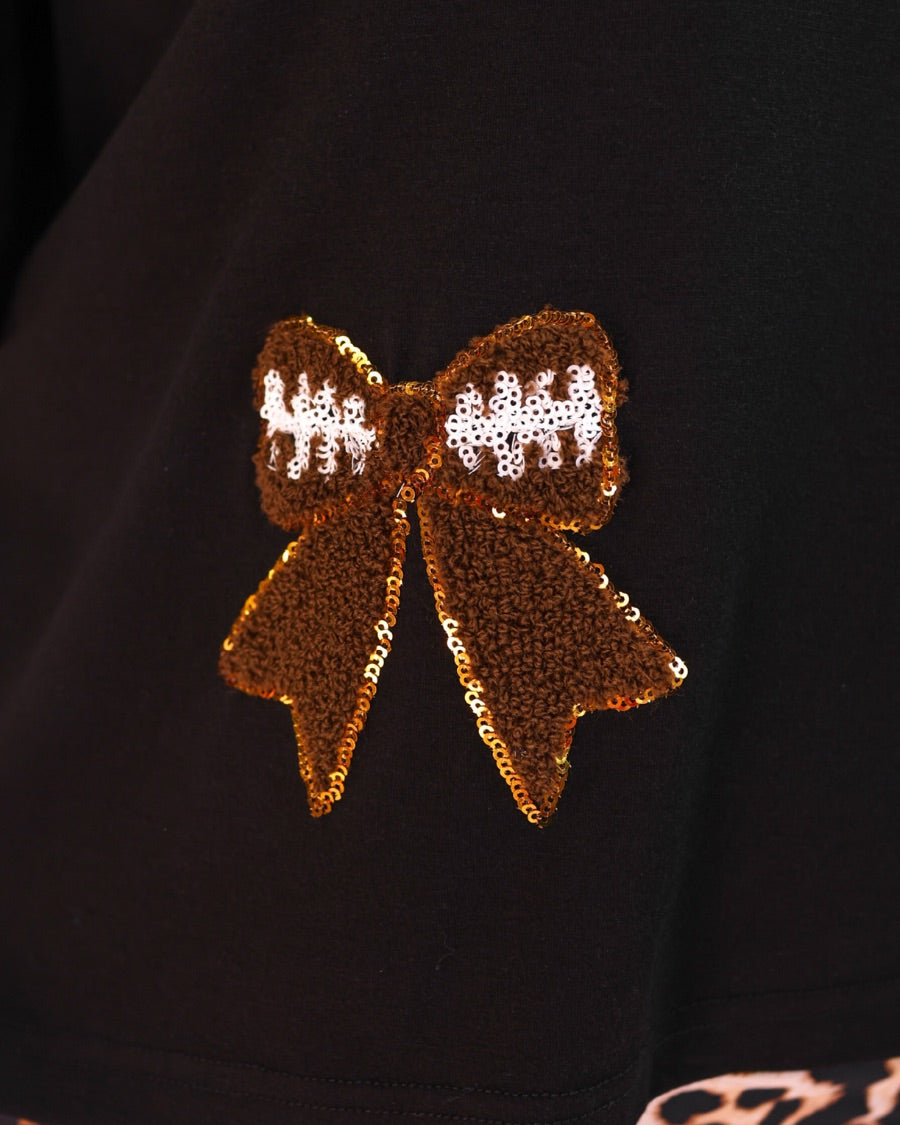 fluttery ruffle short-sleeve top with a mom crop length, sewn-on chenille football bow patches outlined in sequins on a soft, stretch-knit fabric in black