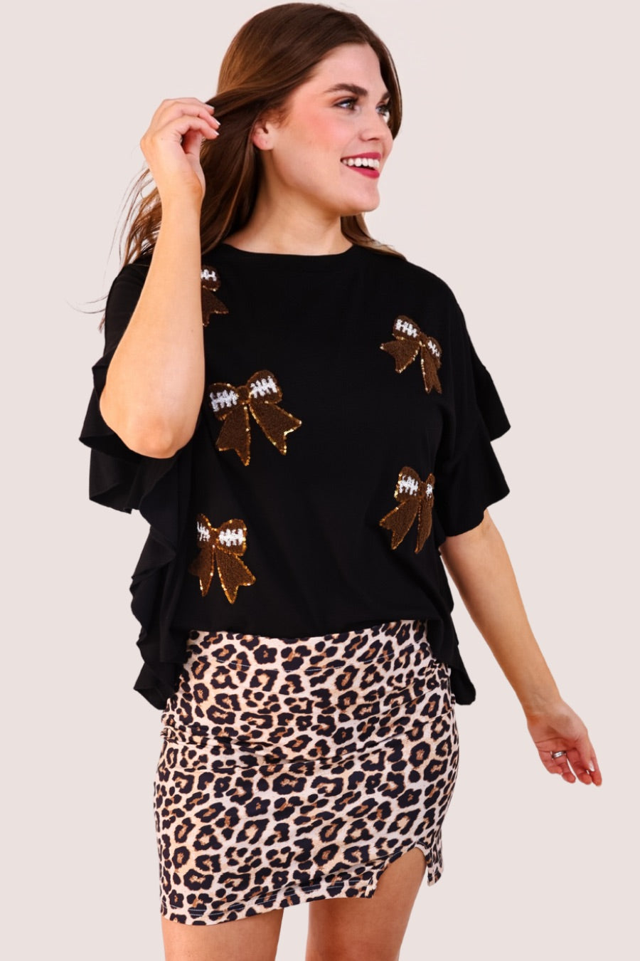fluttery ruffle short-sleeve top with a mom crop length, sewn-on chenille football bow patches outlined in sequins on a soft, stretch-knit fabric in black