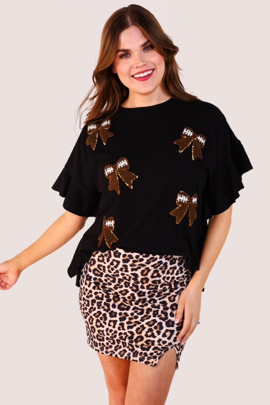 fluttery ruffle short-sleeve top with a mom crop length, sewn-on chenille football bow patches outlined in sequins on a soft, stretch-knit fabric in black