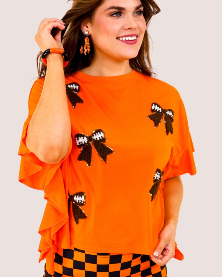 fluttery ruffle short-sleeve top with a mom crop length, sewn-on chenille football bow patches outlined in sequins on a soft, stretch-knit fabric in orange
