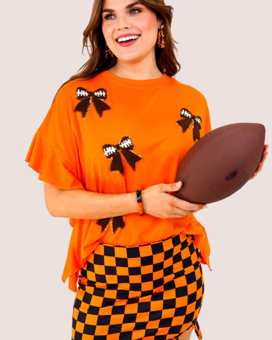 fluttery ruffle short-sleeve top with a mom crop length, sewn-on chenille football bow patches outlined in sequins on a soft, stretch-knit fabric in orange