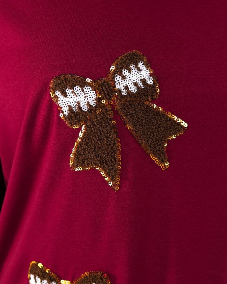 fluttery ruffle short-sleeve top with a mom crop length, sewn-on chenille football bow patches outlined in sequins on a soft, stretch-knit fabric in maroon