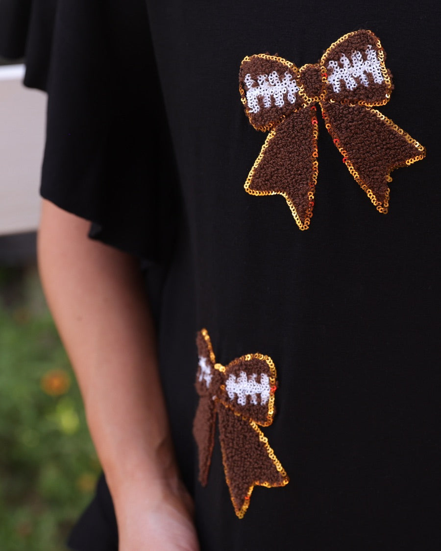 fluttery ruffle short-sleeve top with a mom crop length, sewn-on chenille football bow patches outlined in sequins on a soft, stretch-knit fabric in black