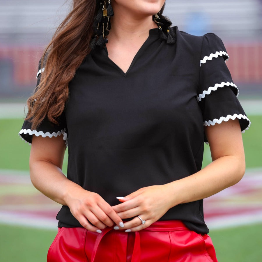 a playful V-neckline top with a ric rac trim detailing on the layered ruffled short sleeves