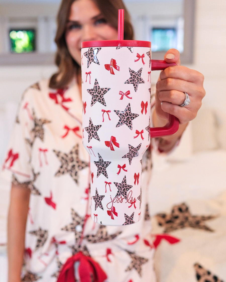 40-ounce white tumbler with a leopard star and red bow pattern print design, handle, screw-on lid, and a reusable straw