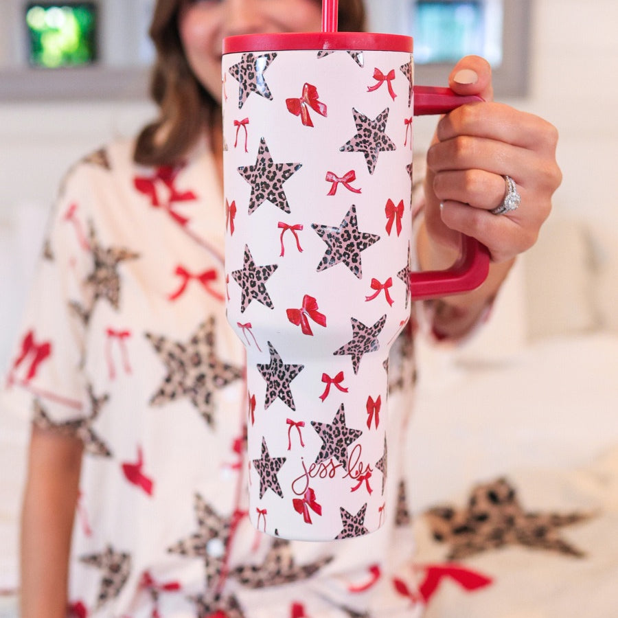 40-ounce white tumbler with a leopard star and red bow pattern print design, handle, screw-on lid, and a reusable straw