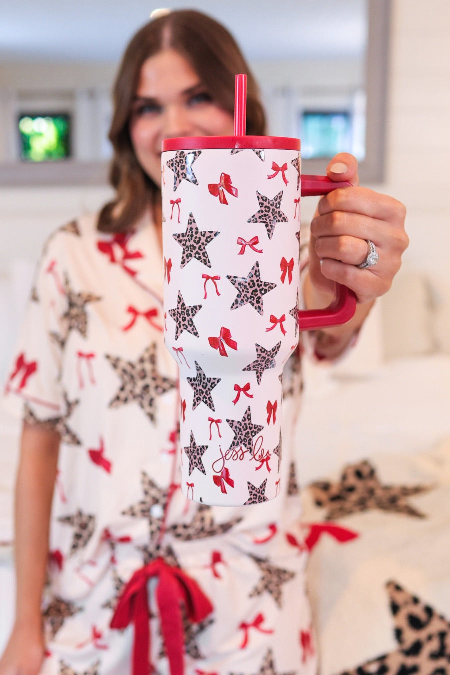 40-ounce white tumbler with a leopard star and red bow pattern print design, handle, screw-on lid, and a reusable straw