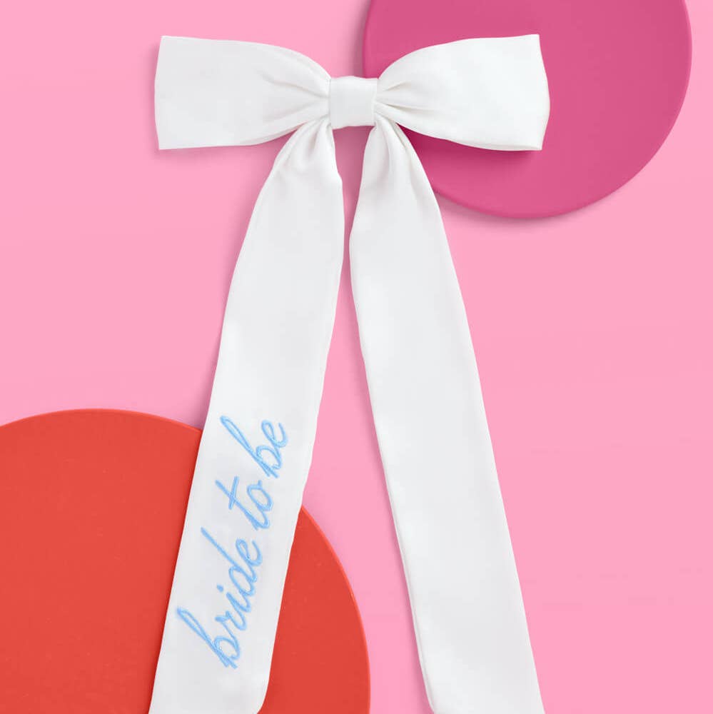 White sash with 'bride to be' text on a pink background