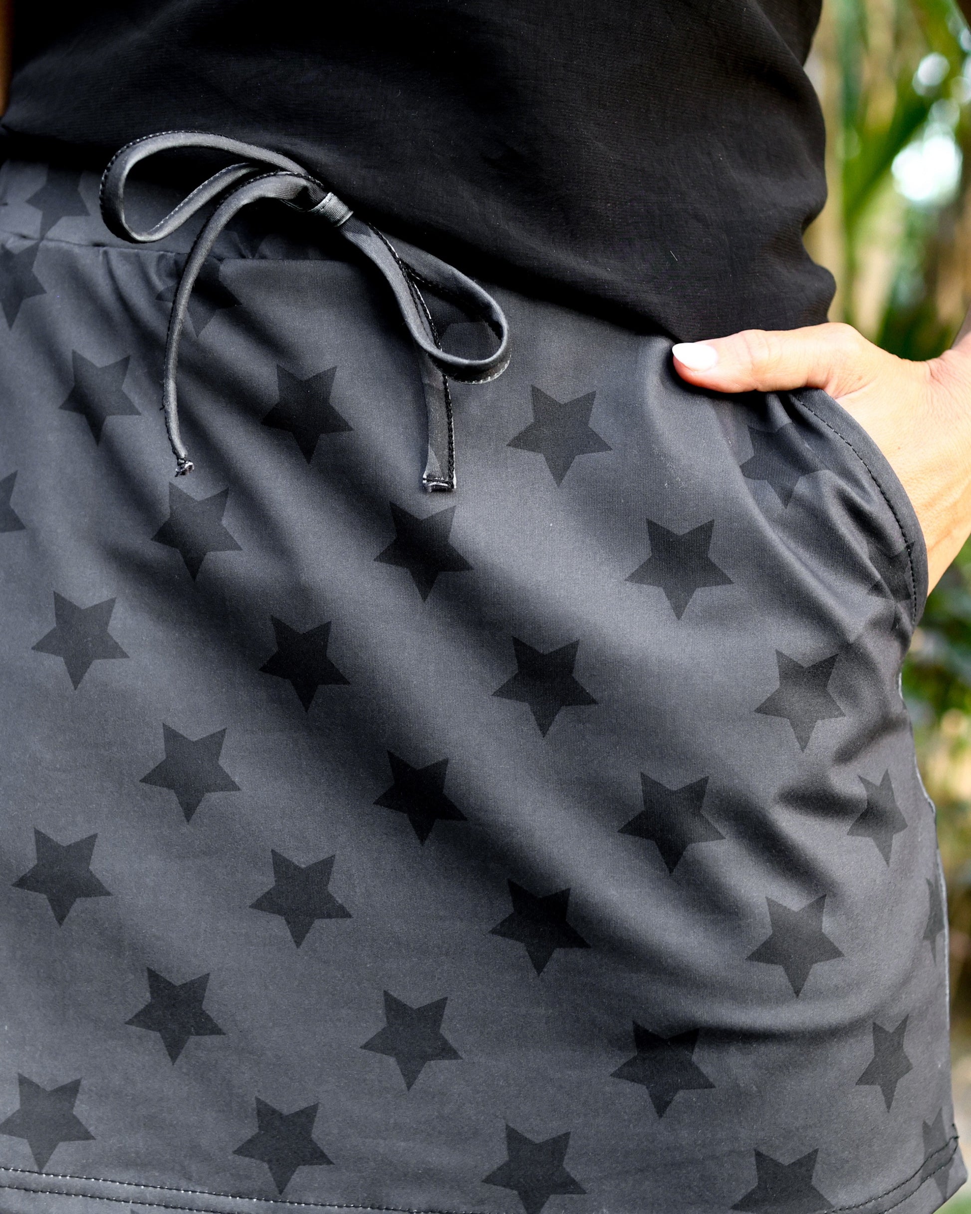 mid-rise relaxed fit everyday skort made of lightweight material with built-in black shorts, drawstring tie, an elastic band on the back, and side pockets, designed on a two-tone black star pattern print